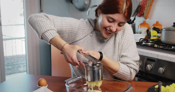 Girl is Mashing Boiled Potatoes for the Preparation of Dumplings and Croquettes