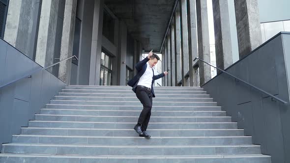 Cheerful happy asian business man dancing walk the stairs backdrop a modern office 