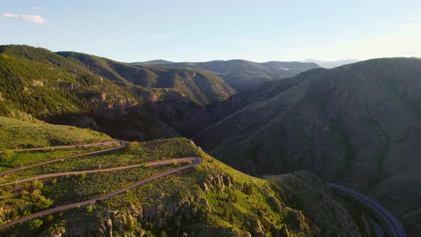 Drone Footage Of Winding Road On Mountain During Beautiful Golden Hour Sunset. Drone Flying Backward