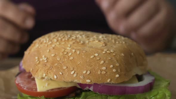 Man Hands Taking Hamburger With Tomato And Onion From Table, Weight Gain