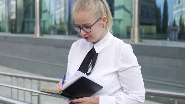 business woman makes entries in the diary on the street