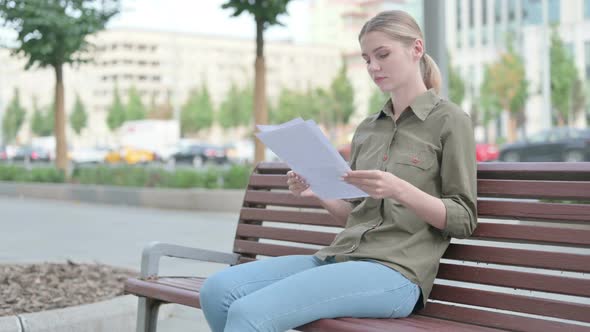 Woman Reading Documents while Sitting on Bench Outdoor