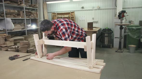 Carpenter Working in a Shirt with a Beard in the Workshop at Work