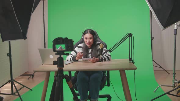 Asian Woman Waving Hand While Playing Game On Mobile Phone On Green Screen With Light Equipment