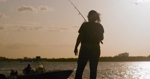 4K Silhouette of Latinx woman with fishing rod against pretty sunset