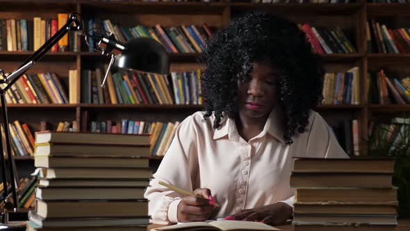 AfricanAmerican Woman Writes in Notebook in Public Library