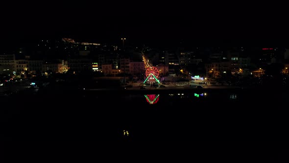 Aerial view of small amusement park with lights at night in Greece.