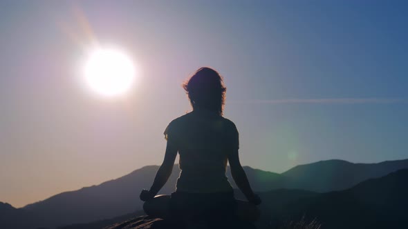 Yoga in Mountains at Sunrise Woman Meditating in the Lotus Position