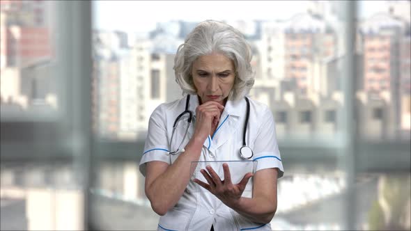 Old Severe Female Doctor with Blank Transparent Glass Copyspace Tablet