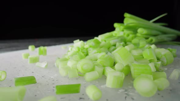 Pieces of Green Onion Stalks Chopped on a Gray Plastic Board
