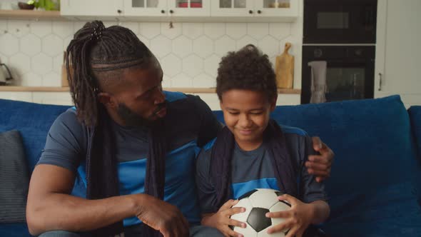 Caring African Father Cheering Up Upset Son with Soccer Ball After Team Defeat