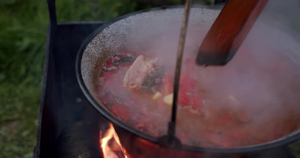 Large Spoonful of Mushroom Soup Which Is Cooked in a Large Cauldron on an Open Fire. Slow Motion V4