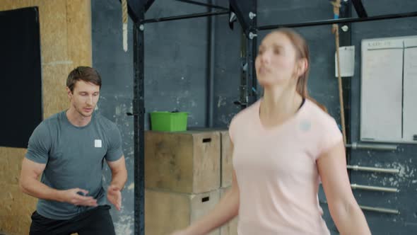 Girl Skipping with Jump Rope While Guy Instructor Clapping Hands Motivating Student