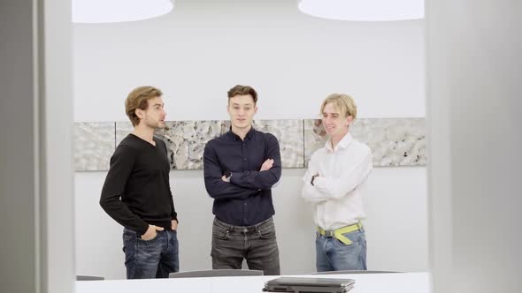 Three Positive Caucasian Coworkers Standing in Conference Room Talking