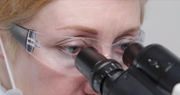 Woman Scientist Using Microscope in a Laboratory. alt