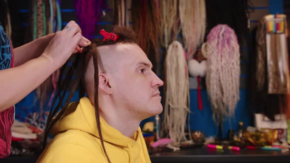 Unrecognizable Person Makes Hairstyle for Young Man in Salon