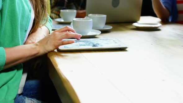 Woman using digital tablet while having coffee