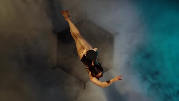 Dancer Spins on a Pole in Blue Smoke and Performs Tricks . Slow Motion. Top View