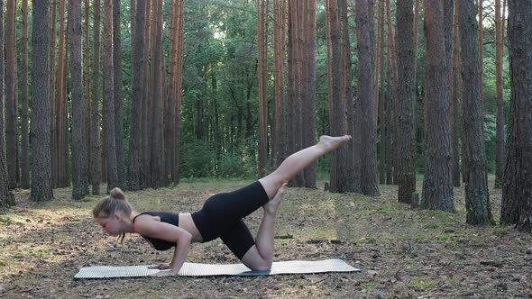 Flexible Fit Lady Practices Yoga Performs Rajakapotasana at Sunny Pine Forest