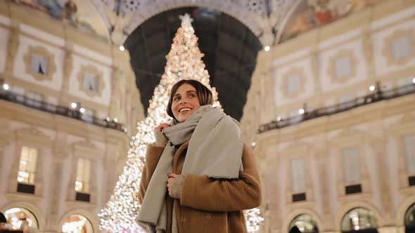 A girl poses against the background of a New Year tree in the evening Milan city