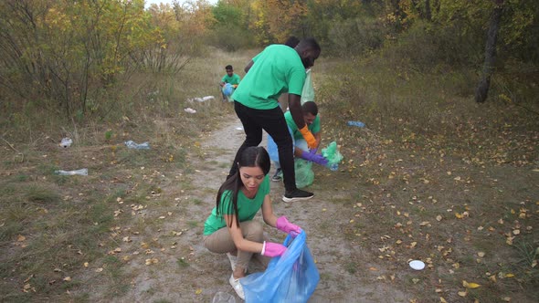 Multi-ethnic Activists Collecting Trash in Forest