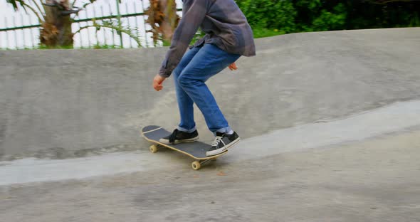 Front view of young caucasian man practicing skateboarding on ramp in skateboard park 4k