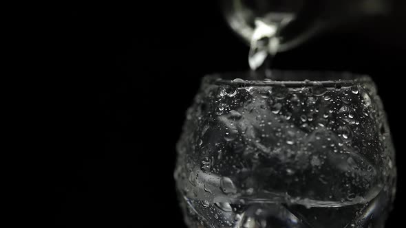 Pouring Up Shot of Vodka Into Glass. Black Background. Pour of Alcohol Drink