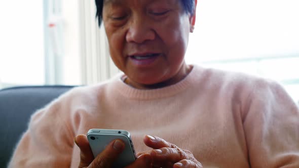 Senior woman using mobile phone in living room