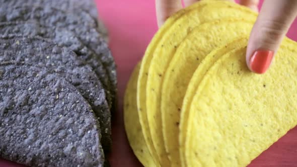 Blue and yellow corn taco shells on a pink background.