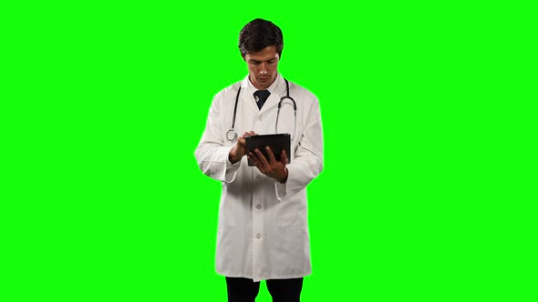 Front view of a doctor using his digital tablet with green screen
