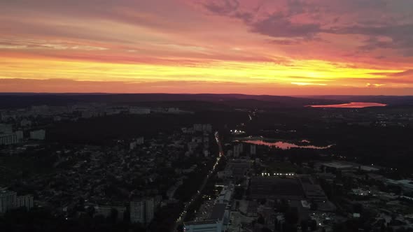 Aerial drone view of Chisinau, Moldova at sunset. Lakes, nightlights, roads with cars, buildings