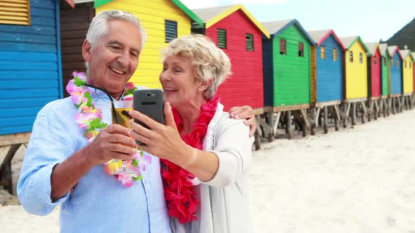 Senior couple taking a selfie on the beach