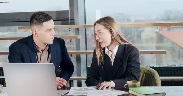 Man and a Woman Discussing Work in the Brightly Lit Modern Office. Concerned Male and Female Working