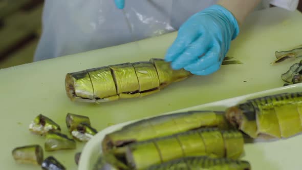 Female Worker Cutting Pieces of Smoked Fish at Fish Factory. Fish Processing Plant. Fish of Cold Hot