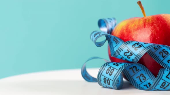 Apple and Centimeter Tape on a Blue Background Rotating Weight Loss and Healthy Eating Close Up