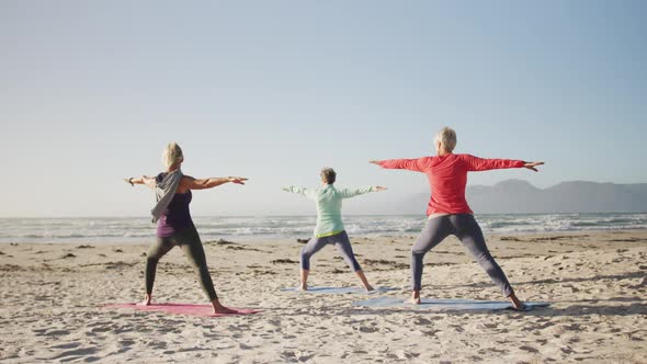 Athletic women performing yoga in the beach