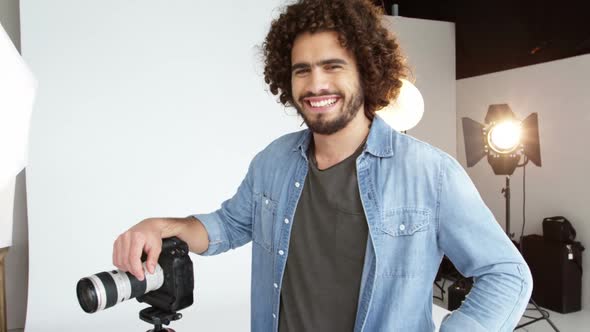 Photographer standing with digital camera in studio