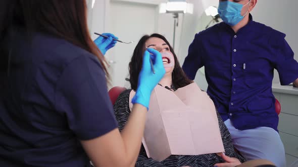 Doctors Dentists Woman and Man in Medical Masks Serve Patient in Dental Clinic