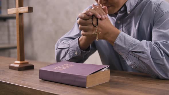 A young Christian man sitting in a church praying to God. alt