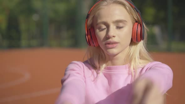 Close-up of Young Happy Caucasian Woman in Headphones Singing and Smiling on Sunny Summer Day