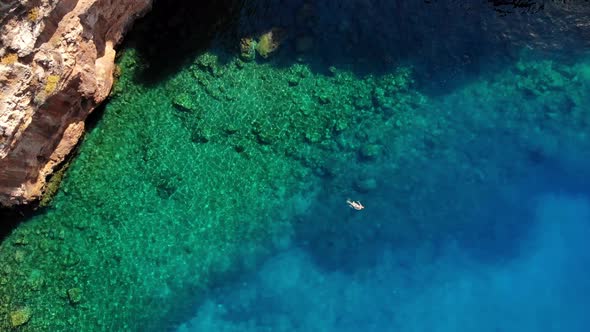 Aerial Top View of Woman Who Lies on Waves on Water in Blue Aquamarine Water and Rests