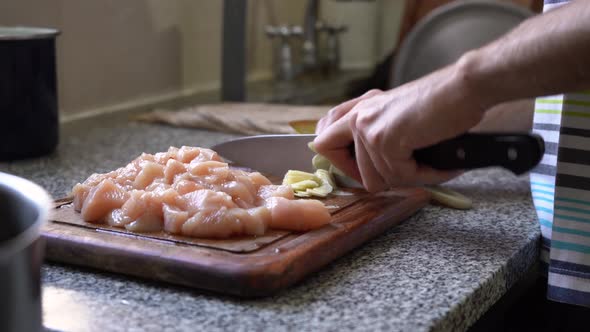 Slicing Garlic With Chicken Meat On The Chopping Board. - close up
