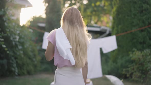 Satisfied Confident Young Beautiful Woman Hanging White Cloth on Shoulder Walking to Clean Laundry