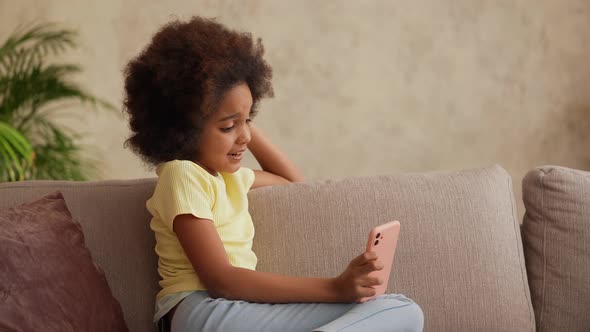 Portrait Little African American Girl Views Information on a Smartphone