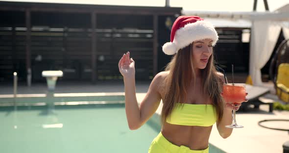 Woman in Christmas Hat Drinking a Cocktail By Pool