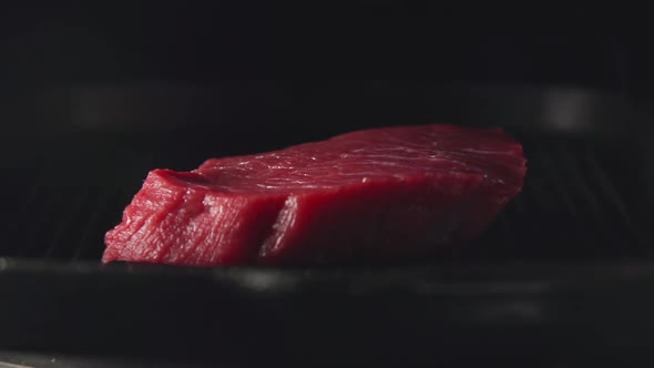 Human Hand Puts A Steak Of Meat On A Grill