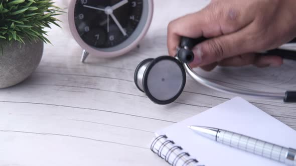 Close Up of Doctor Hand Putting Stethoscope on Table 