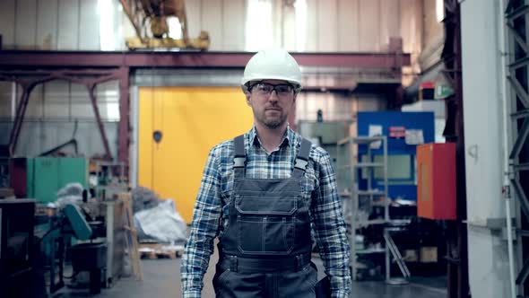 Engineer in Hard Hat is Moving Through a Heavy Industry Factory with a Tablet Computer