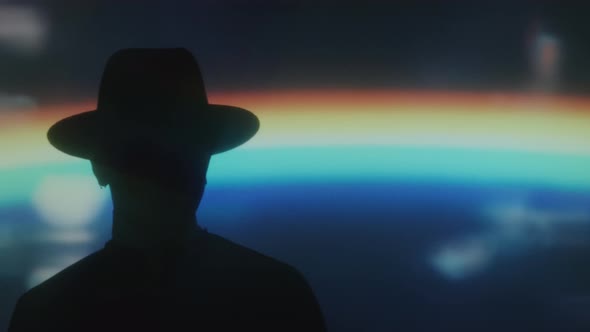 Silhouette of Man in Hat in Room with Rainbow Projection