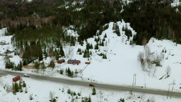 Driving On The Road Through Snow-covered Landscape By The Mountain In Haugastol, Norway. aerial dron